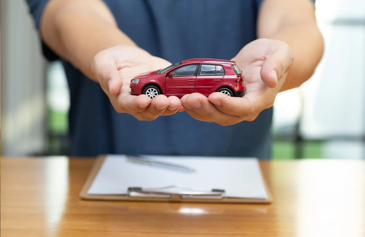 Une personnen tenant une voiture jouet rouge en ses mains.